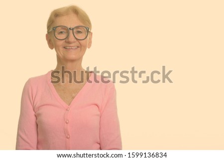 Studio shot of happy senior nerd woman smiling while wearing geeky eyeglasses
