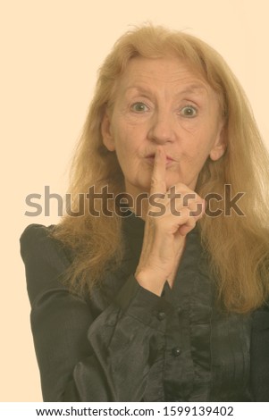 Close up of senior businesswoman with finger on lips