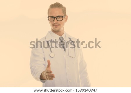 Studio shot of young handsome man doctor giving handshake