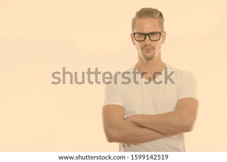 Studio shot of young handsome man wearing eyeglasses with arms crossed