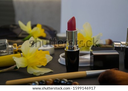 Beautiful yellow daffodils and set of decorative cosmetics, brushes and lipstick, jewelry, perfume, make up and girly stuff, selective focus