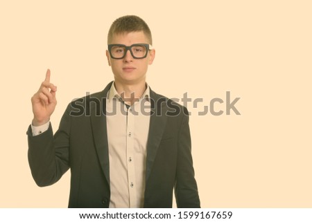 Studio shot of young businessman pointing finger up
