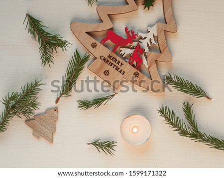 Wooden decoration Christmas tree with red deer on wooden background . Fir-tree branches And a burning candle