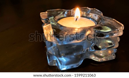 One candle in the glass case on the table