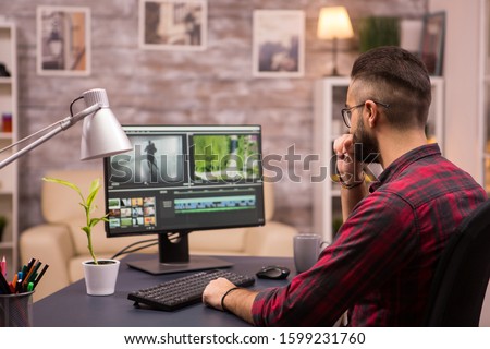 Thoughtful videographer while working in a movie on computer from home. Royalty-Free Stock Photo #1599231760