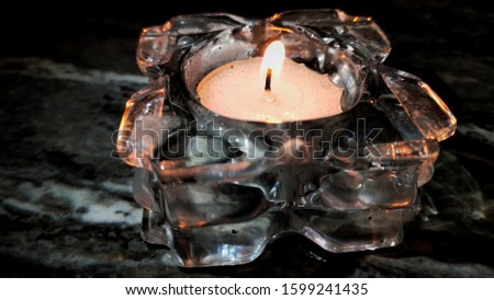 romantic candle flame in a glass container with a dark ceramic background