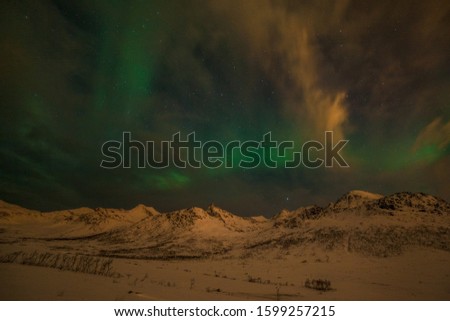 northern lights, Polar lights with many clouds and stars on the sky over mountains in the North of Europe , Tromso, Norway, long shutter speed.