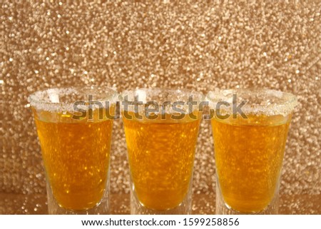 Glasses with a yellow drink. Background from gold spangles.