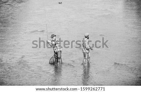 A team above all. Camping on the shore of lake. two happy fisherman with fishing rod and net. concept of a rural getaway. hobby. wild nature. father and son fishing. Poaching. Big game fishing.
