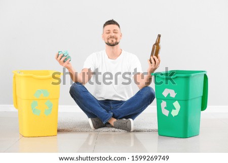 Meditating man with containers for garbage on light background. Concept of recycling