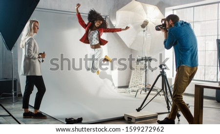Backstage of the Photo Shoot: Moment Photographer Taking Photos of Jumping Beautiful Black Model with Professional Camera. Fashion Magazine Studio Photoshoot
