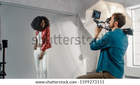 Beautiful Black Model Posing for a Video Clip, Cameraman Filming Her. She plays with Facial Expressions. Stylish Fashion Magazine. Photo Shoot done with Pro Equipment in a Studio