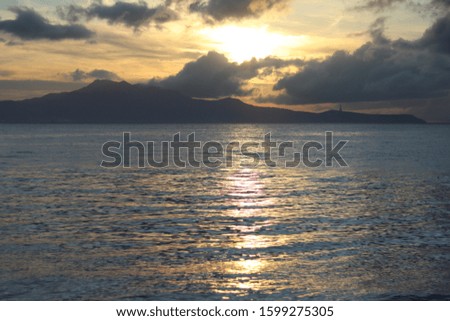 Sunrise view with reflection of light in the water and shadow of the island