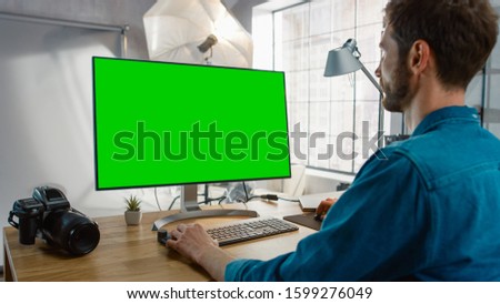 Backstage of the Photoshoot: Photo Editor Works on Desktop Computer with Green Mock-up Screen Display. Fashion Internet Magazine