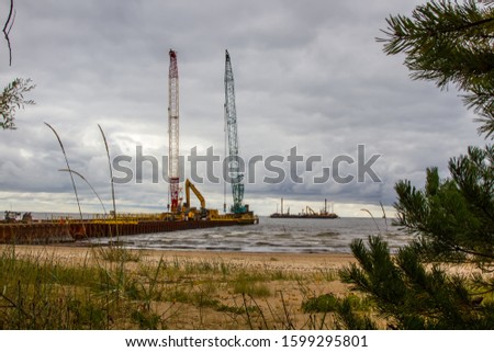 Coast of Narva Bay, Russia: pine, sandy beach and dunes, thickets of European dune grass. In background see pier from which gas pipe Nord Stream 2 are laid in shallow water