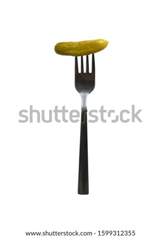 Pickled cucumber on a fork on a white plate. Food and vegetables.