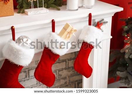 Christmas socks with gifts hanging on fireplace in room