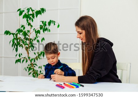 mother and young son draws a picture at the table
