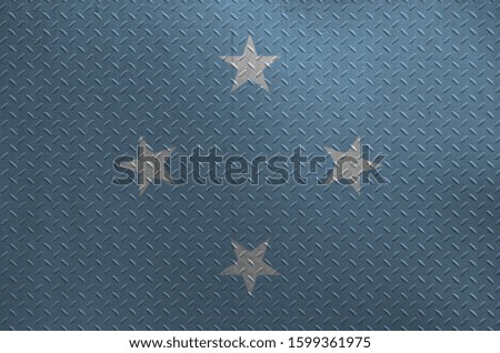 Micronesia flag depicted in paint colors on old brushed metal plate or wall closeup. Textured banner on rough background