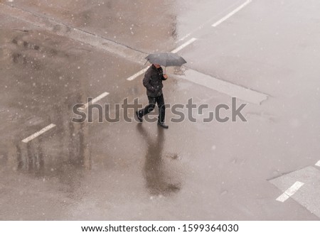 It is raining a man walks down the street. top view