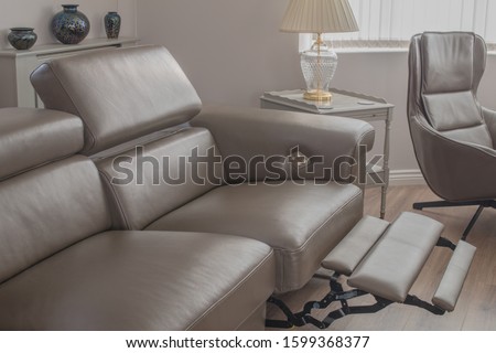 Grey Leather sofa recliner in open position in living room, with side table and single chair. Royalty-Free Stock Photo #1599368377