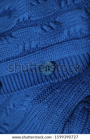 Seamless knitted fabric with pigtails. Knitted sweater with buttons. Knitted background. Classic Blue color 2020