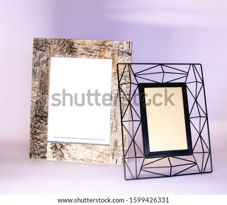 Picture of two frames on a light grey background. One frame is natural and made of wood and the other is made of mettal, black collor and modern.