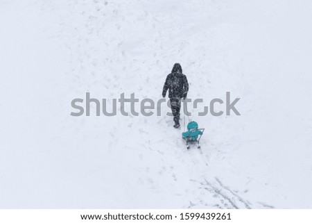Father takes his son in a sleigh in the snow on a lake