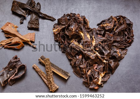 The image of the Heart is laid out from treats for dogs. Natural dried treats for dogs on a dark background. Treats for motivation at dog shows and training. Pet care. Pet supplies. Selective focus. 