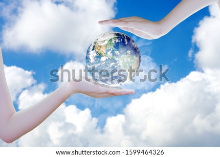 An arm holding the earth into copy space of blue sky. Concept save the earth with your hand.Elements of this image furnished by NASA .