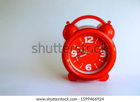 Red alarm clock on a white paper background.