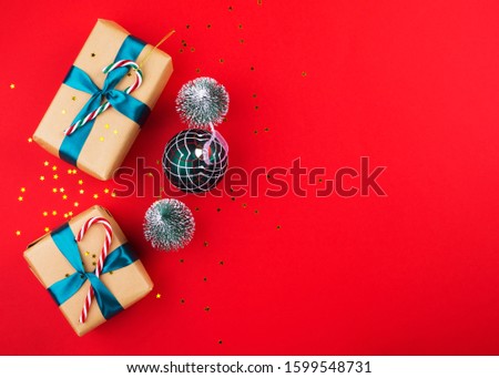 Christmas new year gift boxes wrapped in craft paper with green ribbon and candy canes and ornament on red bold color. Festive flat lay background with copy space. Celebration mood. Boxing day concept