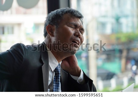 Senior asian businessman experiencing neck pain, office syndrome concept.             