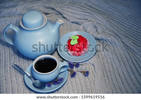 A blue cup with a saucer and a teapot with a bright cake - a red apple and a fragrant strudel on a knitted napkin. Tea, coffee 