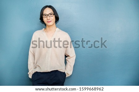 Portrait of attractive beautiful positive long hair asian man. Closeup portrait asian nerdy boy with copy space. Handsome nerd Japanese guy isolated on blue wall background.