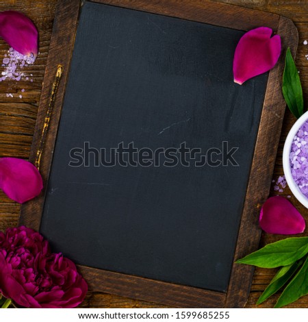 SPA Theme Objects Bath Salt, Fresh Purple Peony Flowers with Black Chalkboard Background Card Concept, Top View. Selective focus.
