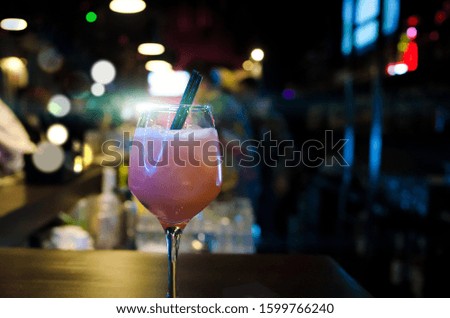 Pink cocktail with two black straw on the bar counter