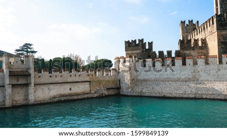 Beautiful view of the real Medieval Castle located on Lake Garda, precisely "Sirmione - Italy". In the picture is visible both the solid Castle and the boathouse with an amazing blue-green water