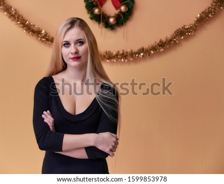 Portrait of a cute girl in a black T-shirt with long beautiful hair and great makeup. Concept of a young blonde woman with New Year's decor. Smiling, showing emotions on a pink background.