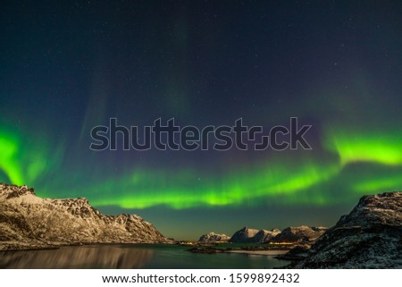 Polar lights, Aurora borealis over fjord, mountains with many stars on the sky in Lofoten islands, Norway, long shutter speed.