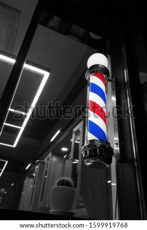 Old-fashioned barber pole in the window, night shot. Barbershop pole in the barber shop, selective focus, vertival image
