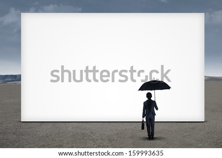 Businesswoman looking at blank billboard under cloudy sky