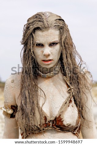 A young woman's face is covered with dirt and filth.
Her hair is tangled in a mess. Her facial expression 
leaves her looking hideous and repulsive.