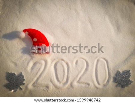 A white background with the  number written as 2020 has a red hat on top of the first 2 numbers and a silver maple leaf on the front and back.