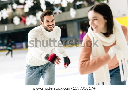 selective focus of cheerful young couple having fun while skating on rink