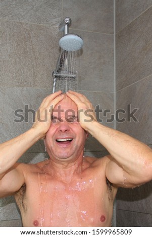 vertical photo of a man who washes in the shower under the stream of water and cries