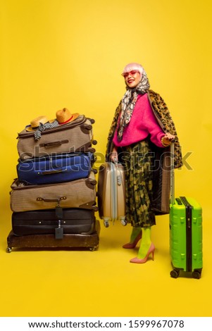 It's hard to be influencer. A lot of clothes for travel to go. Caucasian woman's portrait on yellow background. Beautiful blonde model. Concept of human emotions, facial expression, sales, ad.