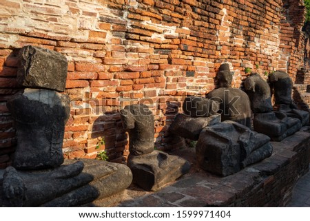 Broken ancient buddha statue and brick wall background.