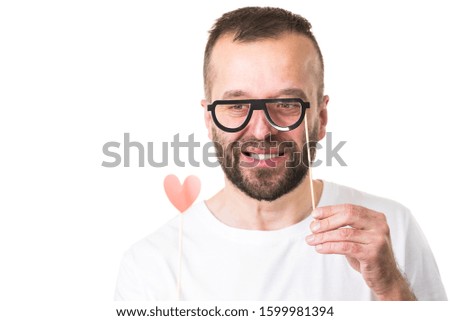 Funny adult guy flirting hoping for romance. Man holding heart shape and eyeglasses on stick, making fun.