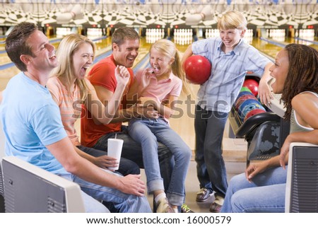 Family in bowling alley with two friends smiling